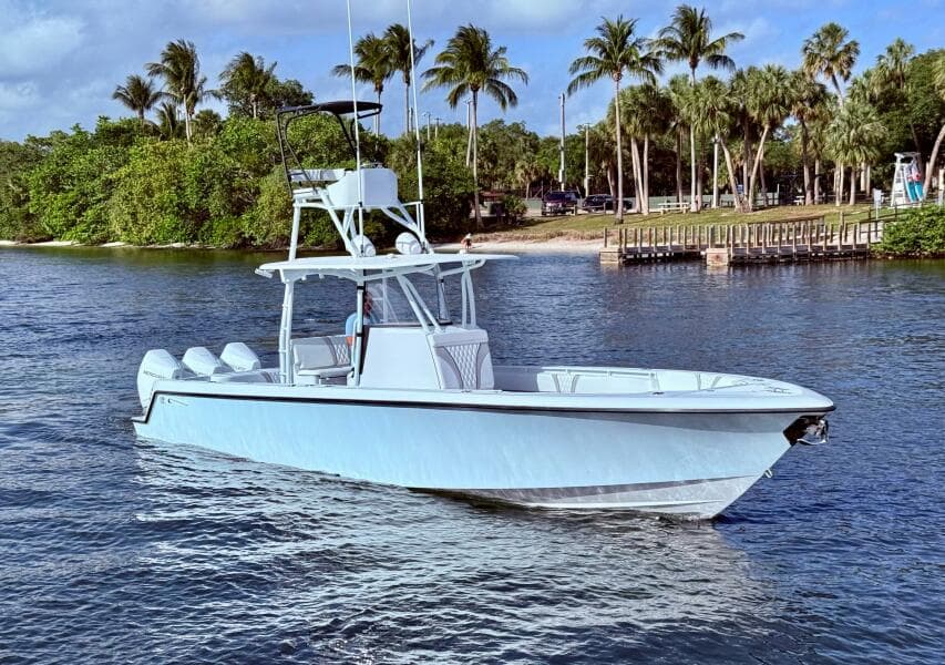 2024 Contender 39 ST boat on water, surrounded by palm trees and a dock.