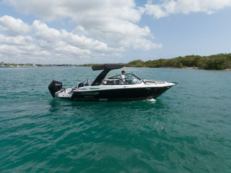 2023 Monterey 255 Super Sport boat cruising on clear blue water under a partly cloudy sky.