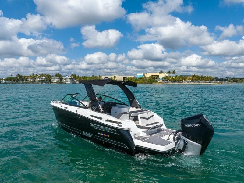 2023 Monterey 255 Super Sport boat cruising on clear blue water under a partly cloudy sky.