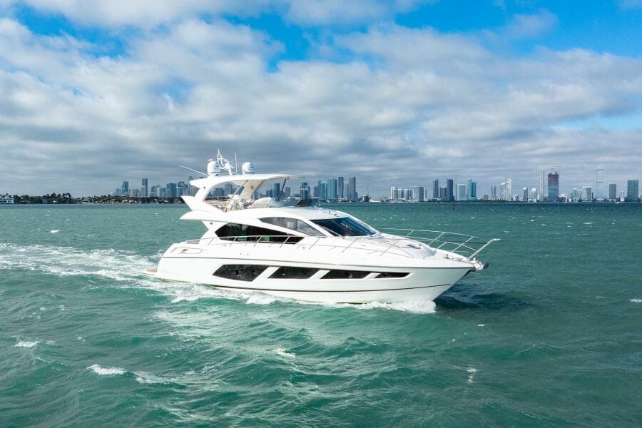 2016 Sunseeker Manhattan 65 yacht cruising on open water with city skyline backdrop.