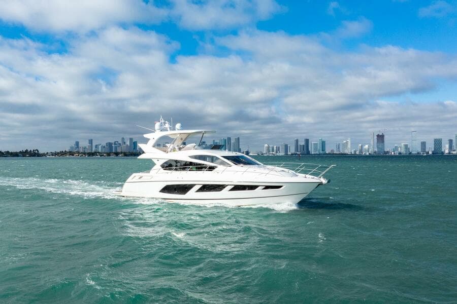 2016 Sunseeker Manhattan 65 yacht cruising on open water with city skyline backdrop.