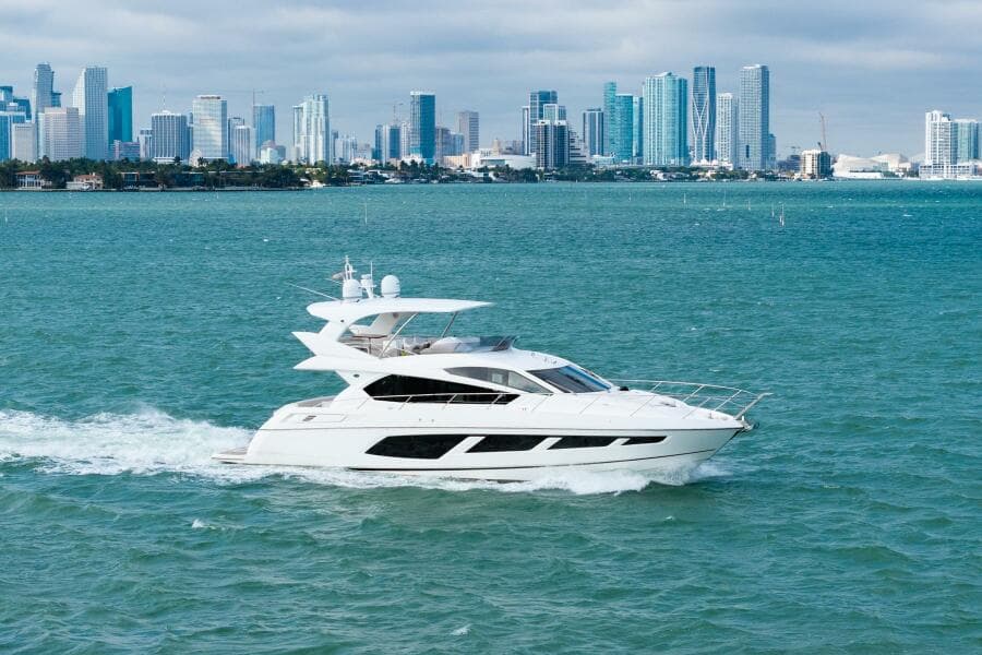 2016 Sunseeker Manhattan 65 yacht cruising near a city skyline.