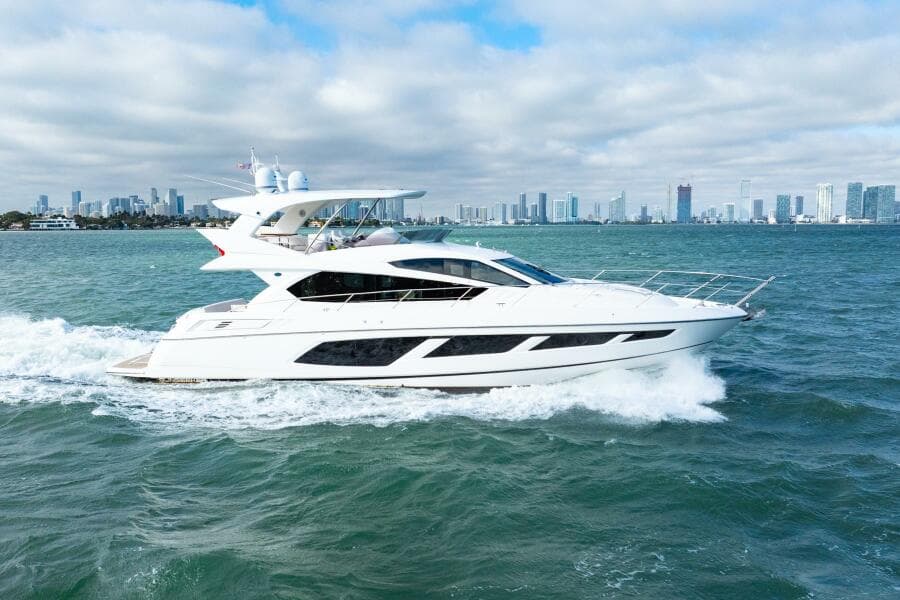 2016 Sunseeker Manhattan 65 yacht cruising on open water with city skyline backdrop.