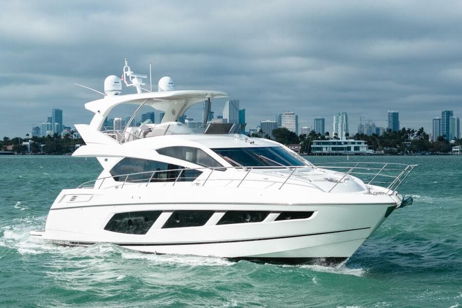 2016 Sunseeker Manhattan 65 yacht cruising on open water with city skyline backdrop.
