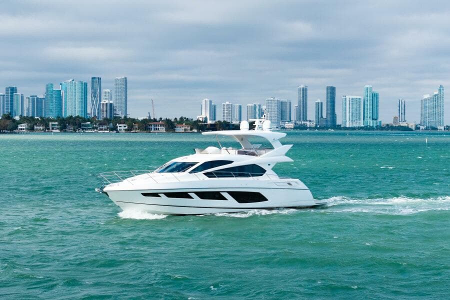 2016 Sunseeker Manhattan 65 yacht cruising near a city skyline.