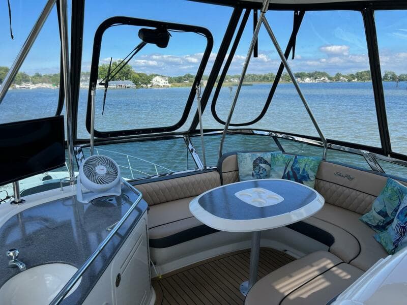 2005 Sea Ray 500 Sedan Bridge interior with seating and table, overlooking serene water view.