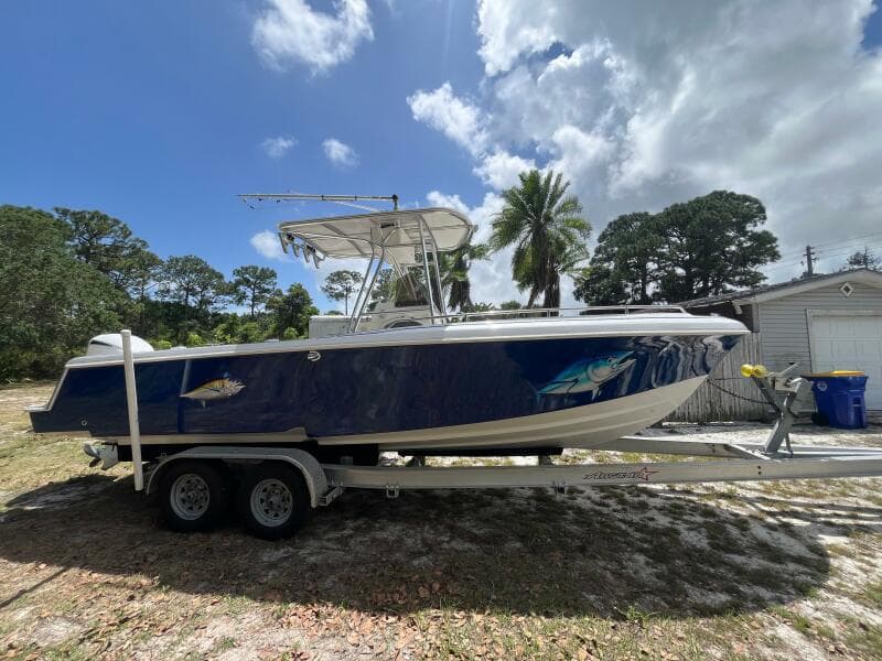 1998 Blue Fin 25 Center Console boat on trailer, parked outdoors under cloudy sky.