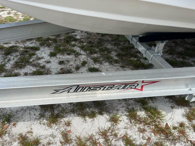 Trailer for 1998 Blue Fin 25 Center Console boat on sandy ground.