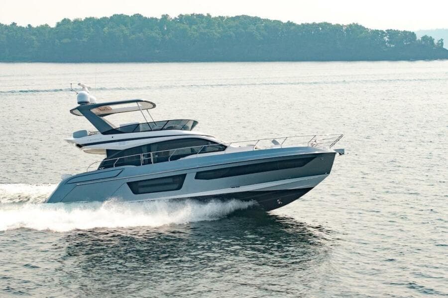 2023 Azimut Fly 53 yacht cruising on a serene lake with lush green shoreline.