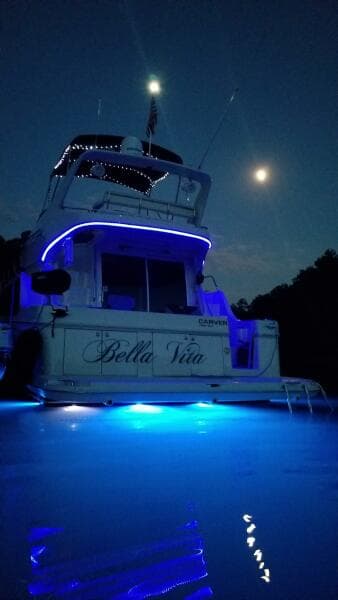 2004 Carver 360 Sport Sedan yacht illuminated at night with blue lights under a moonlit sky.