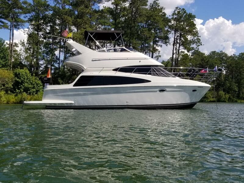2004 Carver 360 Sport Sedan yacht on a serene lake, surrounded by lush trees.