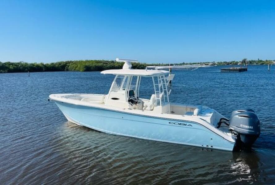 2021 Cobia 301 Center Console boat on calm water, featuring a sleek design and Yamaha engine.
