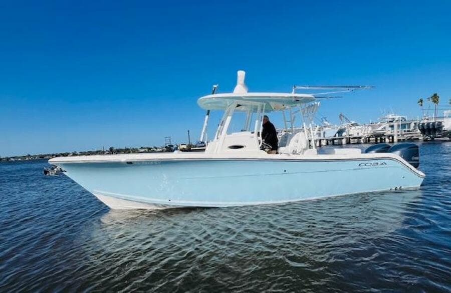 2021 Cobia 301 Center Console boat on calm water under clear blue sky.