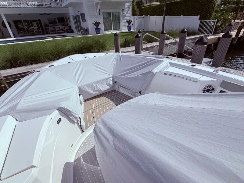 2024 Scout 400 LXF boat covered at dockside near modern waterfront home.