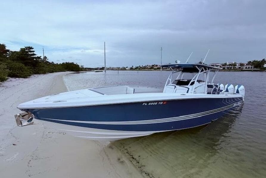2022 Nor-Tech 390 Sport Center Console boat on sandy beach, calm waters, overcast sky.