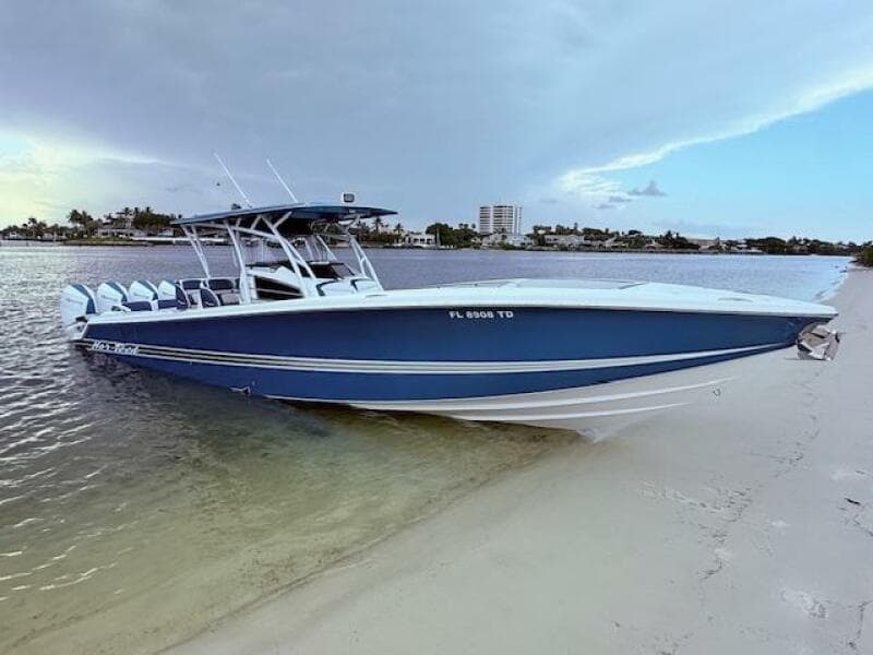 2022 Nor-Tech 390 Sport Center Console boat on sandy shore, calm waters, and cloudy sky.