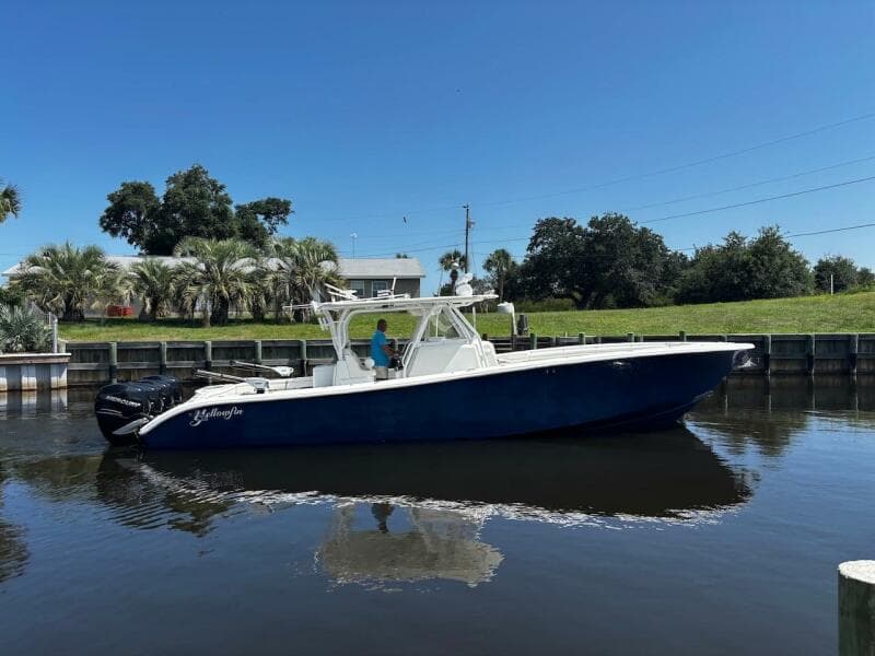 2015 Yellowfin 39 boat on calm water, clear sky, and lush greenery in the background.