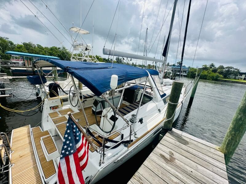 2015 Beneteau Oceanis 45 sailboat docked, featuring blue canopy and American flag.
