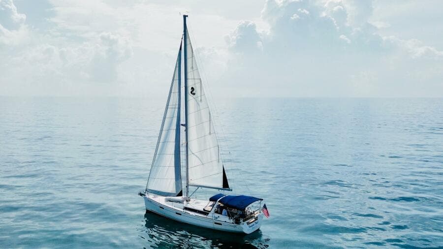 Sailing yacht Beneteau Oceanis 45, 2015 model, on calm ocean waters under cloudy sky.