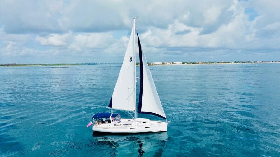 Sailing yacht Beneteau Oceanis 45, 2015 model, cruising on calm blue waters under a cloudy sky.
