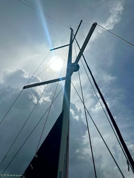 Mast of 2015 Beneteau Oceanis 45 sailboat against cloudy sky and sun.