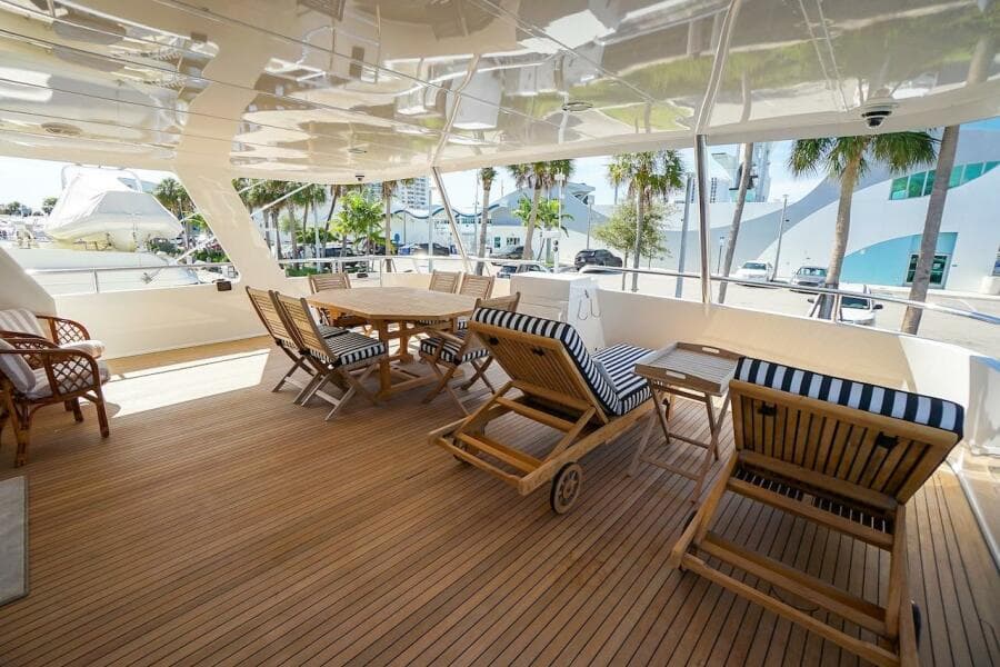 Luxurious deck of 1996 ABD 90 Explorer yacht with wooden furniture and scenic marina view.