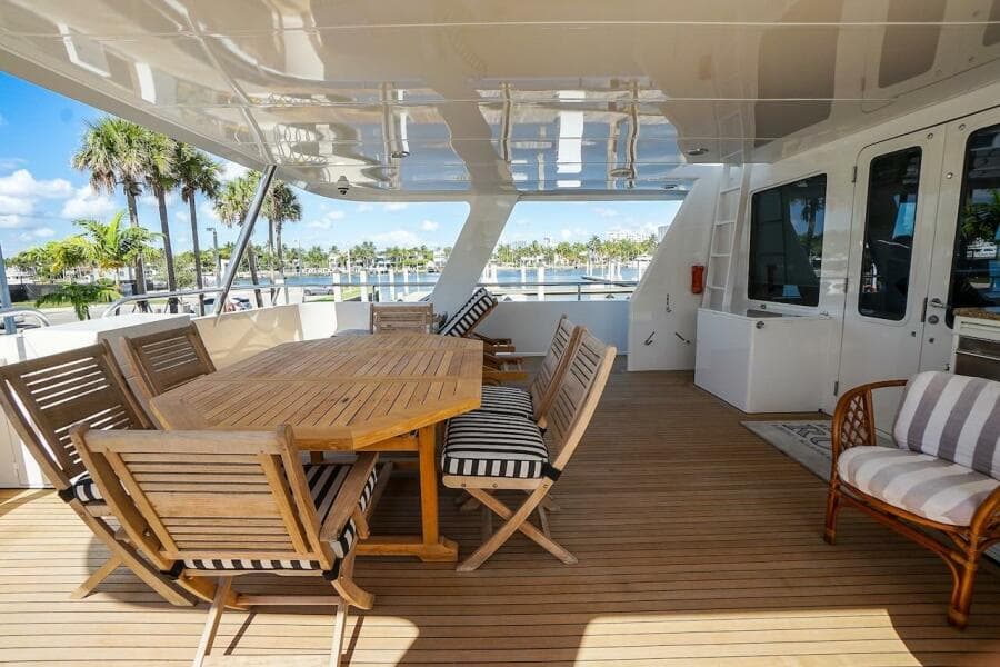 Spacious deck of 1996 ABD 90 Explorer yacht with wooden furniture and scenic marina view.