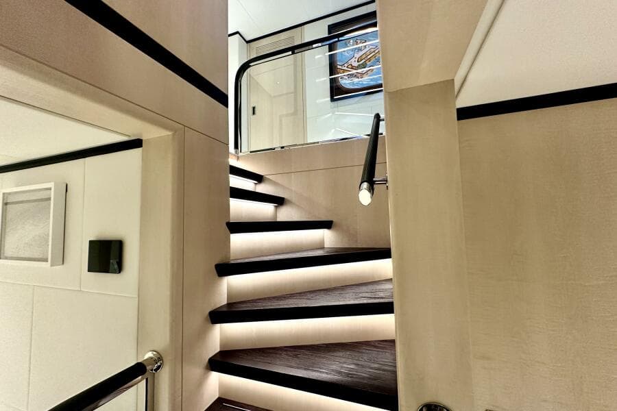 Luxurious interior staircase of 2023 Majesty 120 yacht with modern lighting.