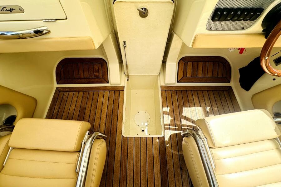 2013 Chris-Craft Corsair 22 interior with teak flooring and beige leather seats.