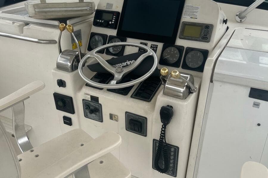 Control panel of a 2001 Pursuit 3000 Offshore boat with steering wheel and gauges.