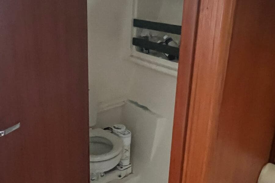 2001 Pursuit 3000 Offshore boat bathroom with wooden door and compact toilet.