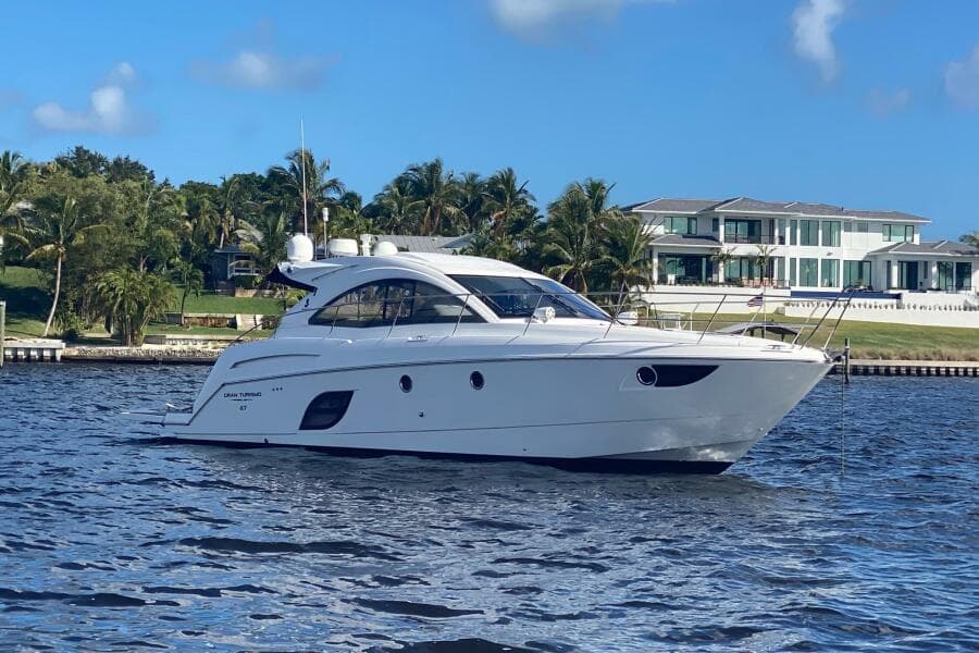 2014 Beneteau Gran Turismo 44 yacht on water, luxury waterfront home in background.