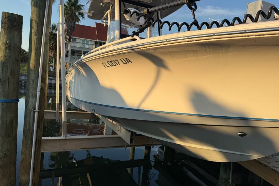 2018 Sea Hunt BX 25 FS boat docked, reflecting sunlight, with palm trees in the background.