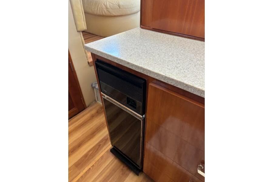 2004 Carver 466 Motor Yacht interior with compact fridge and wooden cabinetry.