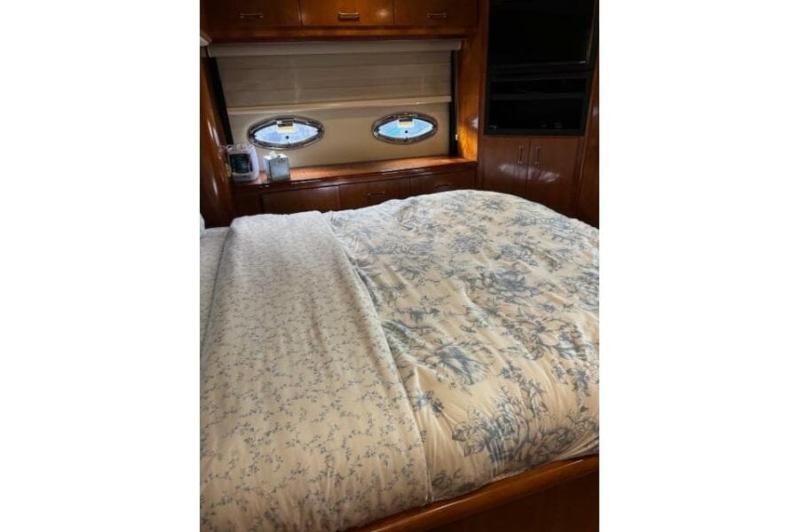 Luxurious bedroom interior of 2004 Carver 466 Motor Yacht with floral bedding and porthole windows.