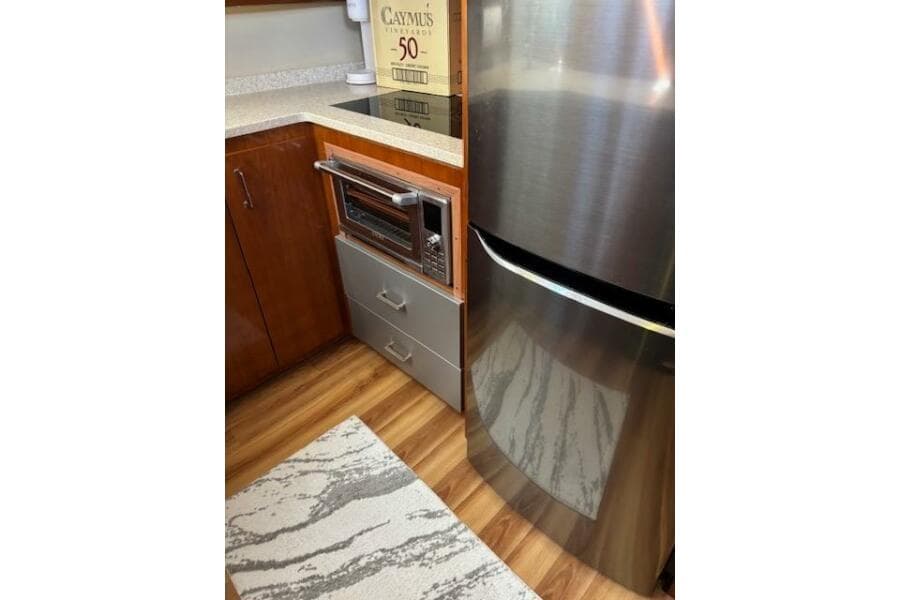 2004 Carver 466 Motor Yacht kitchen with stainless steel fridge, microwave, and wooden cabinetry.