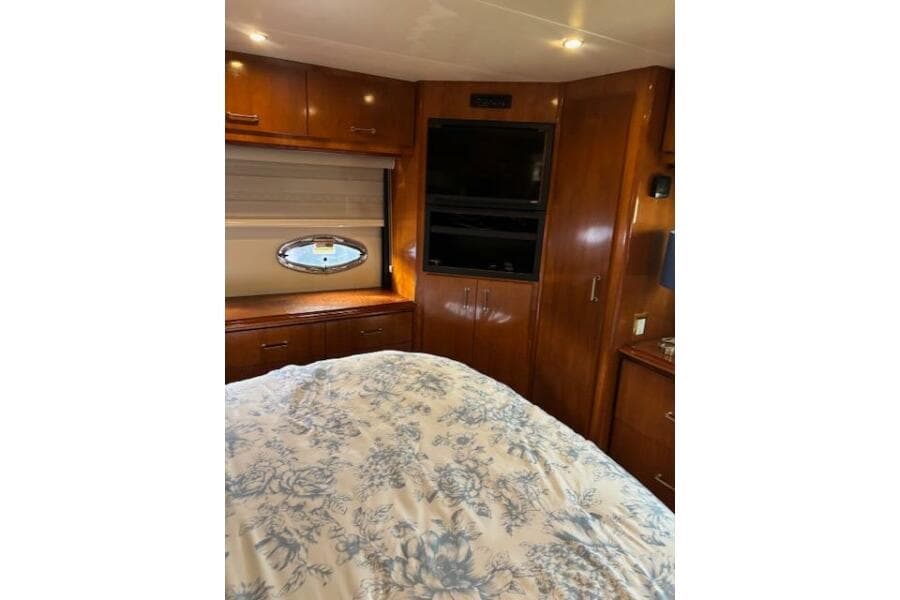 Luxurious interior of 2004 Carver 466 Motor Yacht with wood cabinetry and floral bedding.
