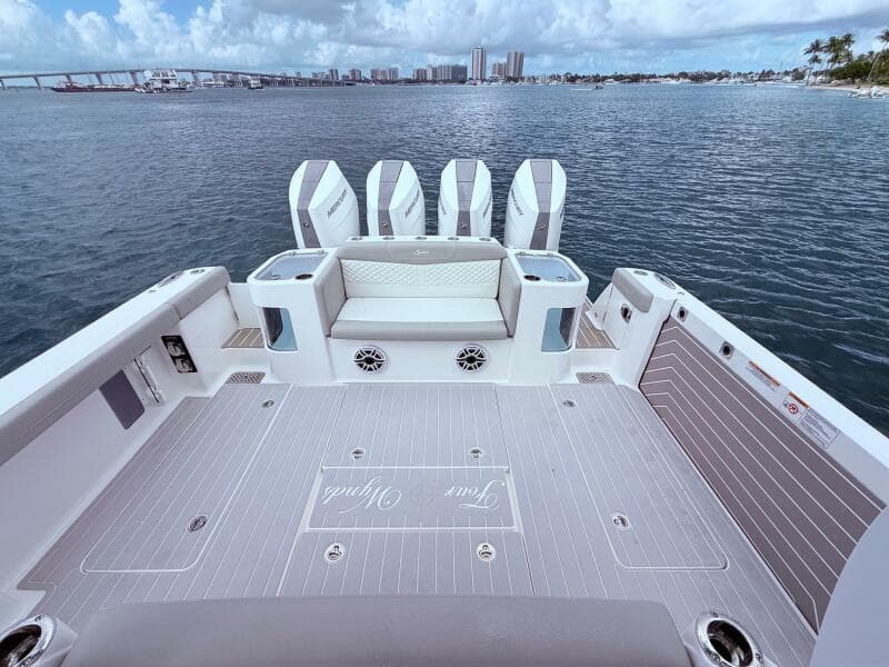 2024 Scout 400 LXF boat deck with four engines, overlooking a scenic waterfront.