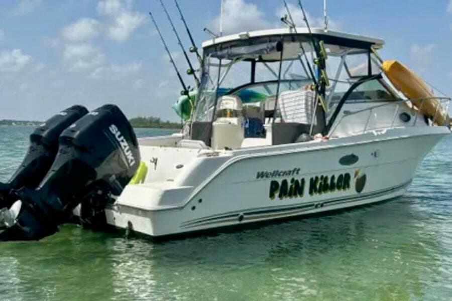 2002 Wellcraft 290 Coastal boat named "Pain Killer" with Suzuki engines in clear water.